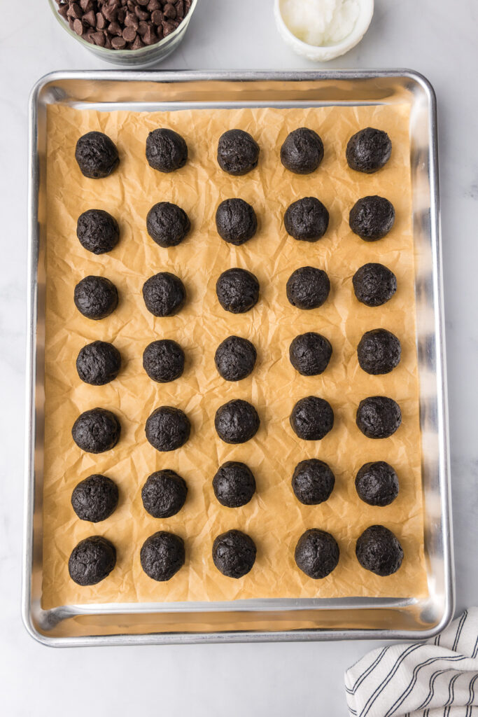 Oreo mint chocolate truffle dough balls on a baking sheet after rolling.