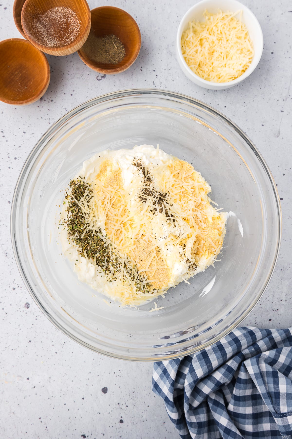 A glass bowl filled with cream cheese, parmesan cheese and other spices for pepperoni dip.