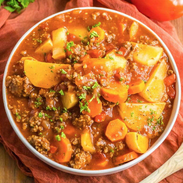 A bowl of Poor Man's stew with ground beef, potatoes and vegetables in a bowl from overhead on a table.