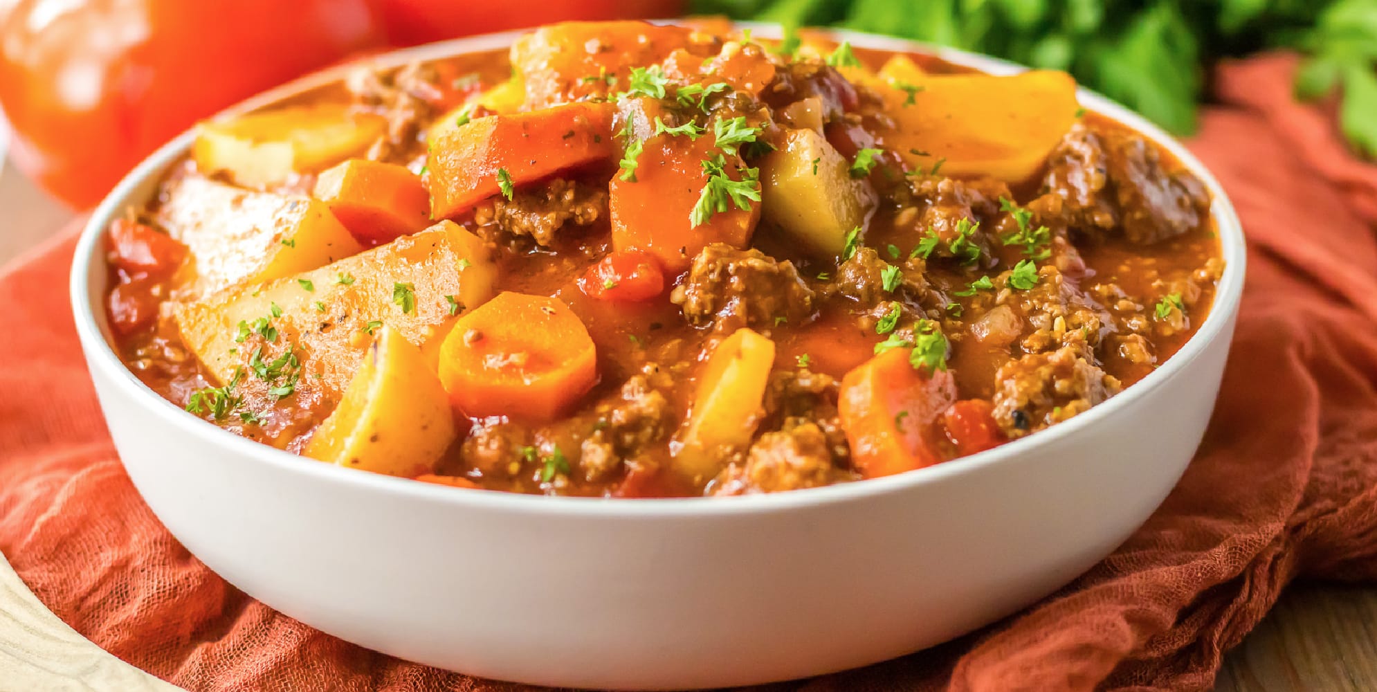 A bowl of poor man's stew with ground meat and vegetables in a bowl looking from the edge.