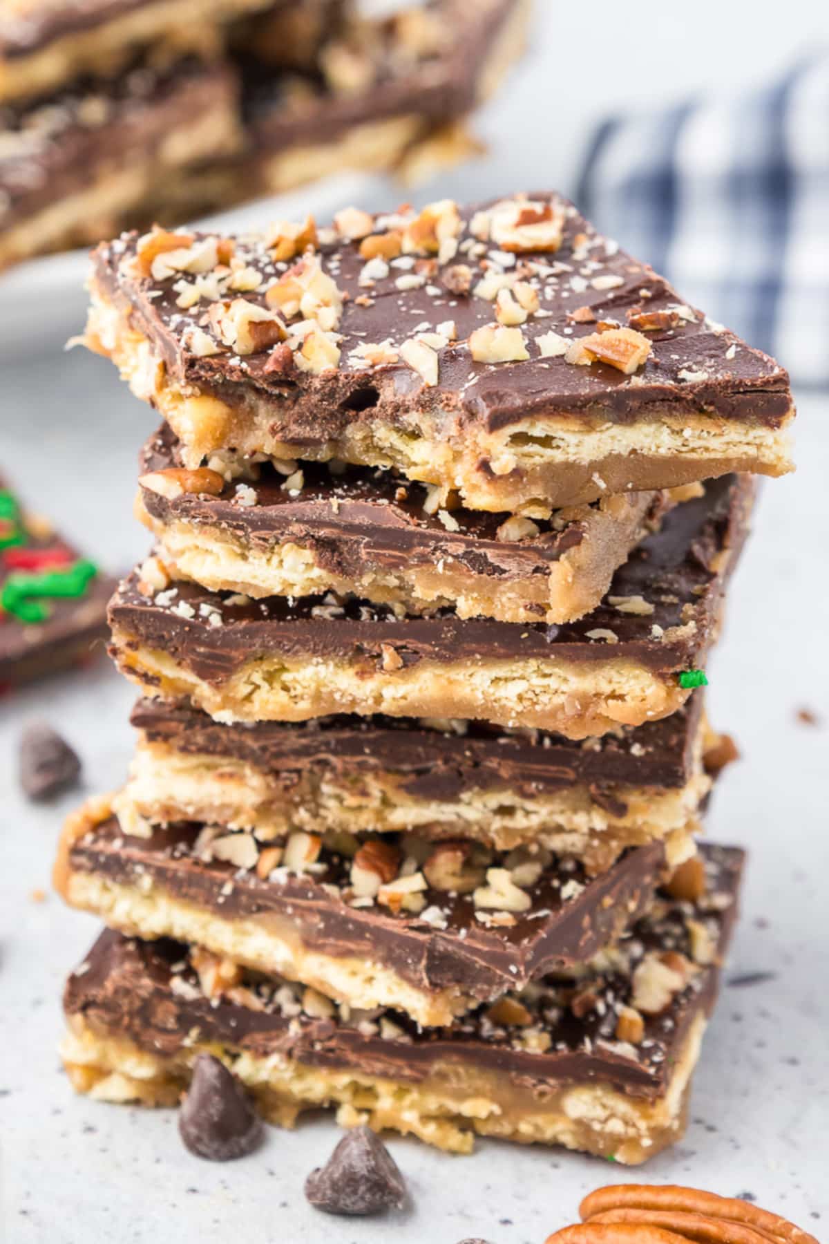 A stack of chocolate and pecan saltine toffee bars with the top piece missing a bite.