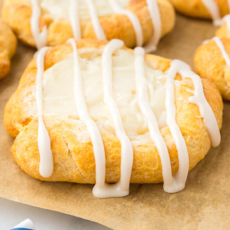 Close up on a crescent roll cream cheese danish with icing drizzled on top.