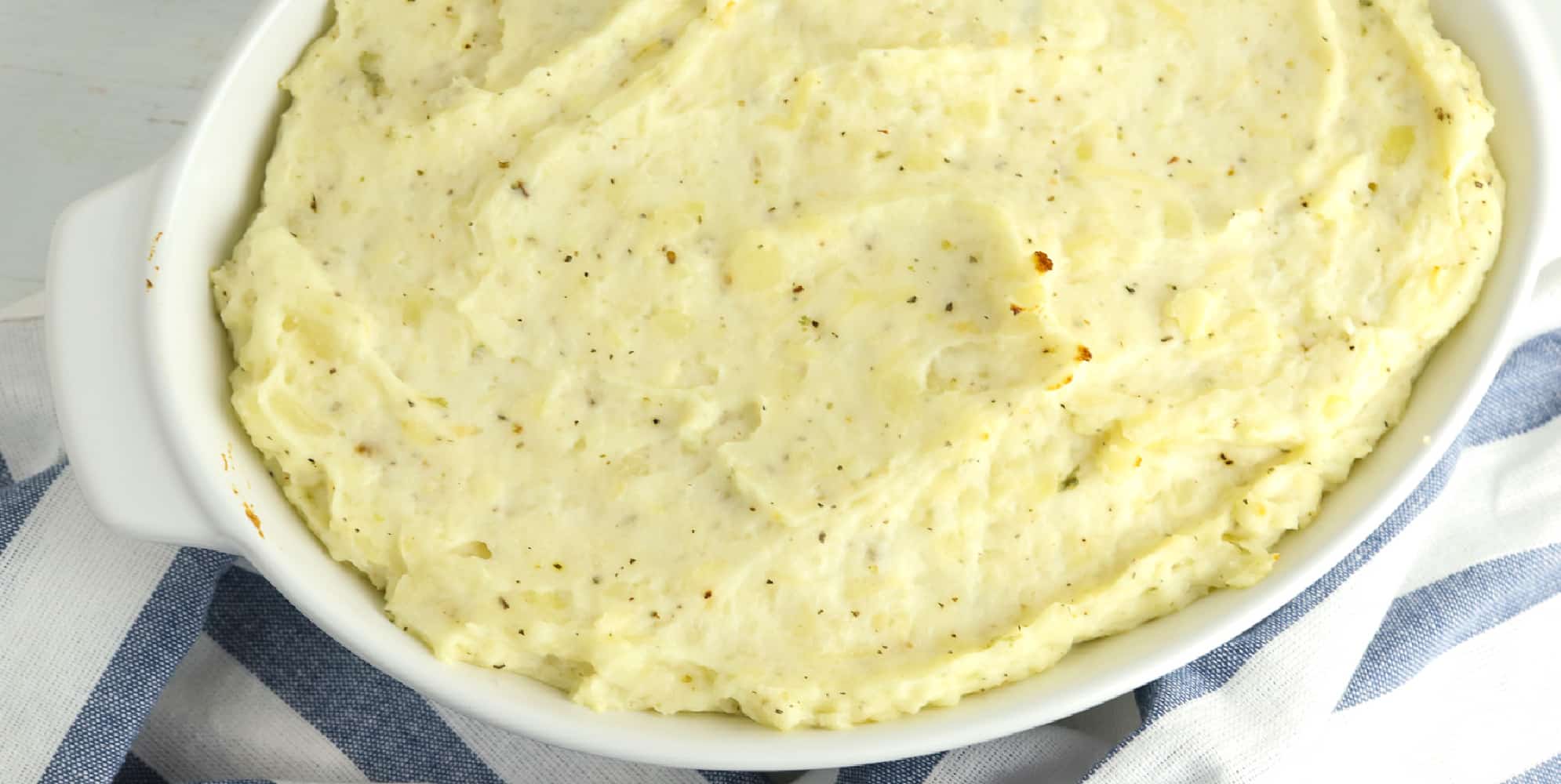 Garlic cream cheese mashed potatoes in a white casserole dish after baking.