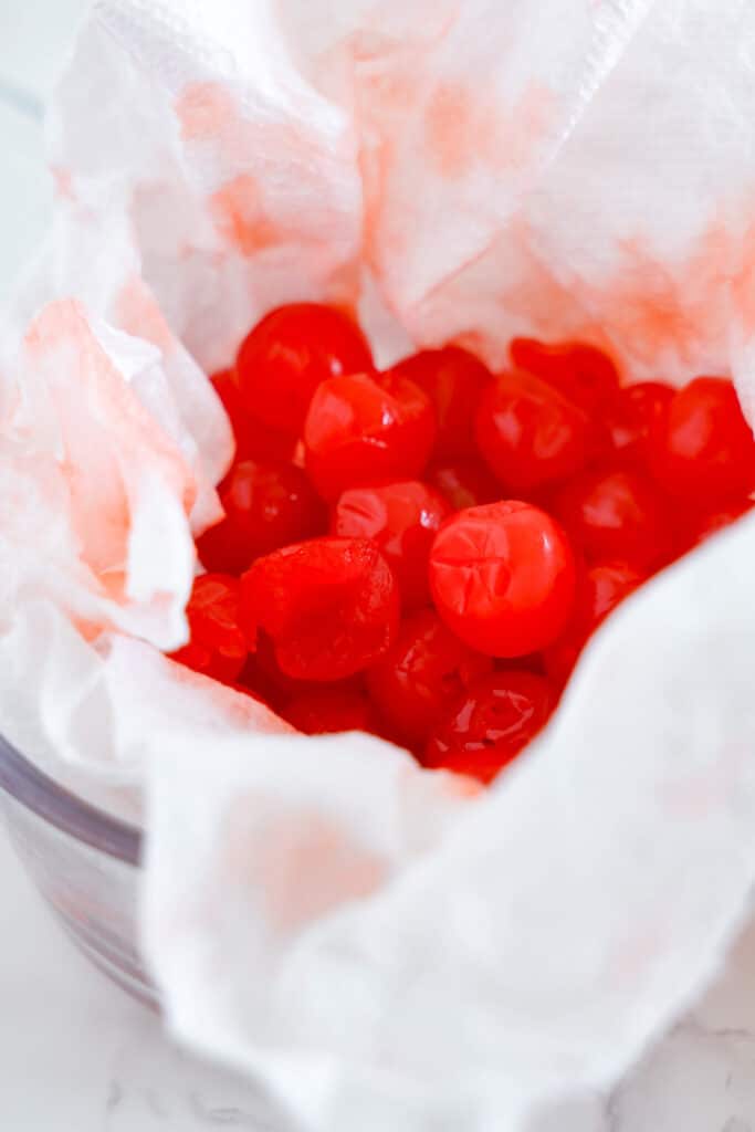 Maraschino cherries being dried in a bowl with paper towels.