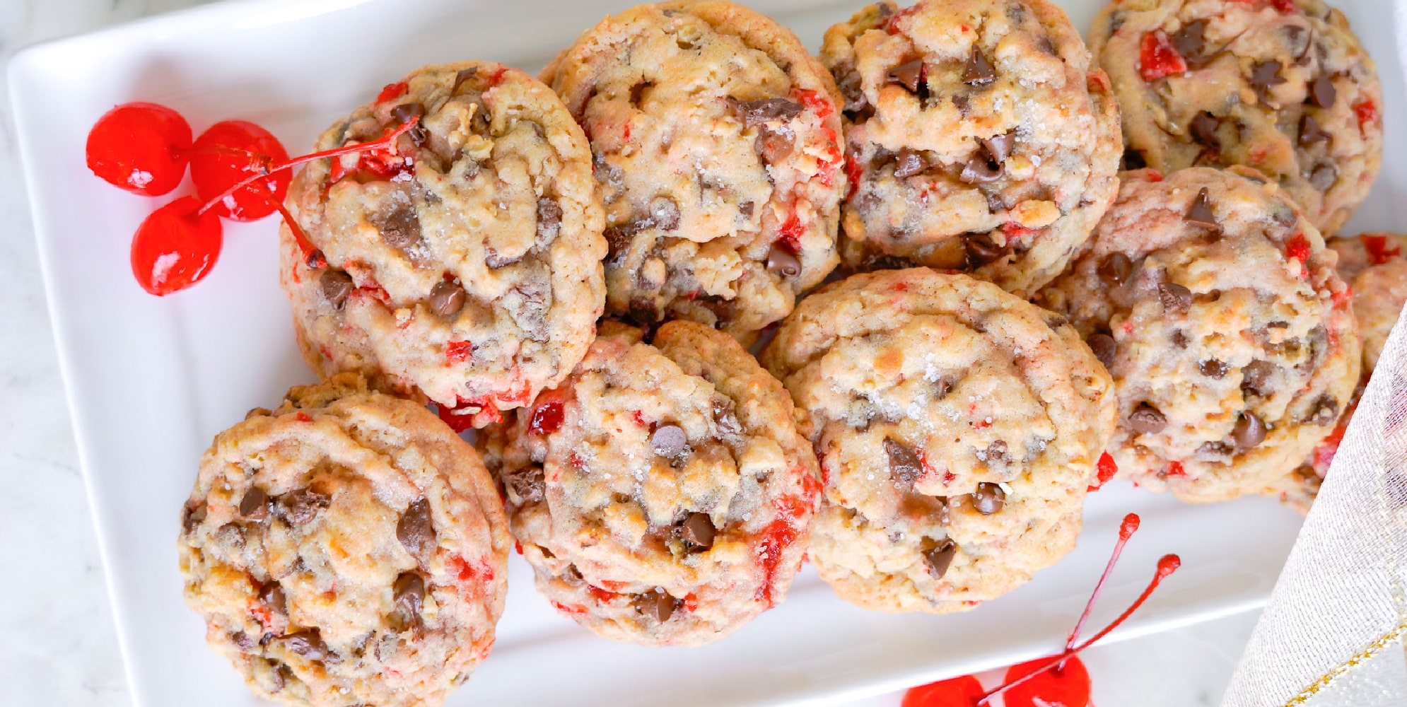 Maraschino cherry chocolate chip cookies piled on a white platter.