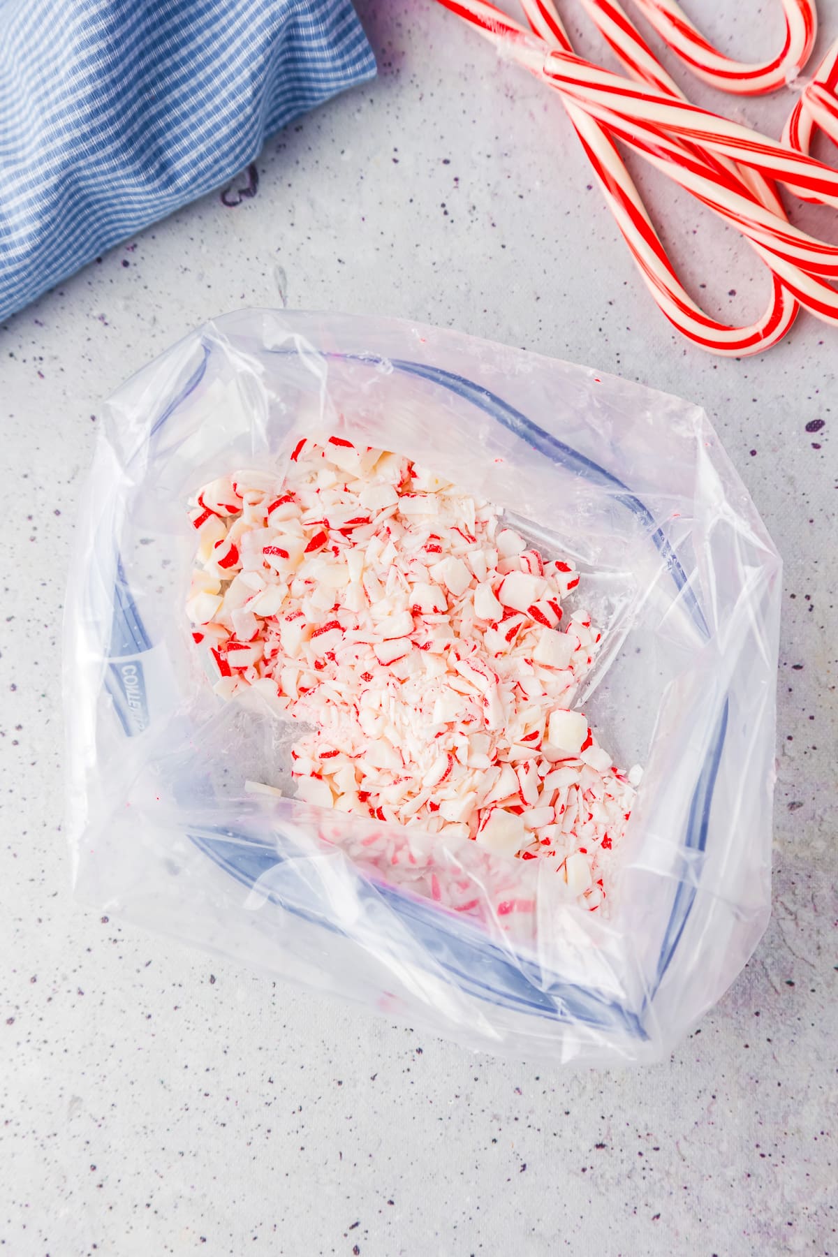 Candy canes in a plastic bag on a table next to candy canes on the table.