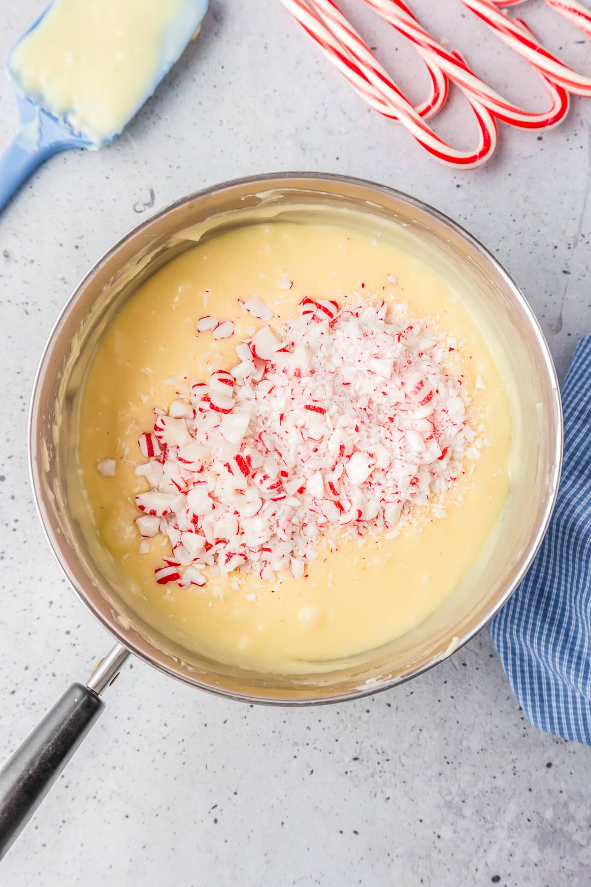 A pan full of liquid fudge with candy cane bits being mixed into it.