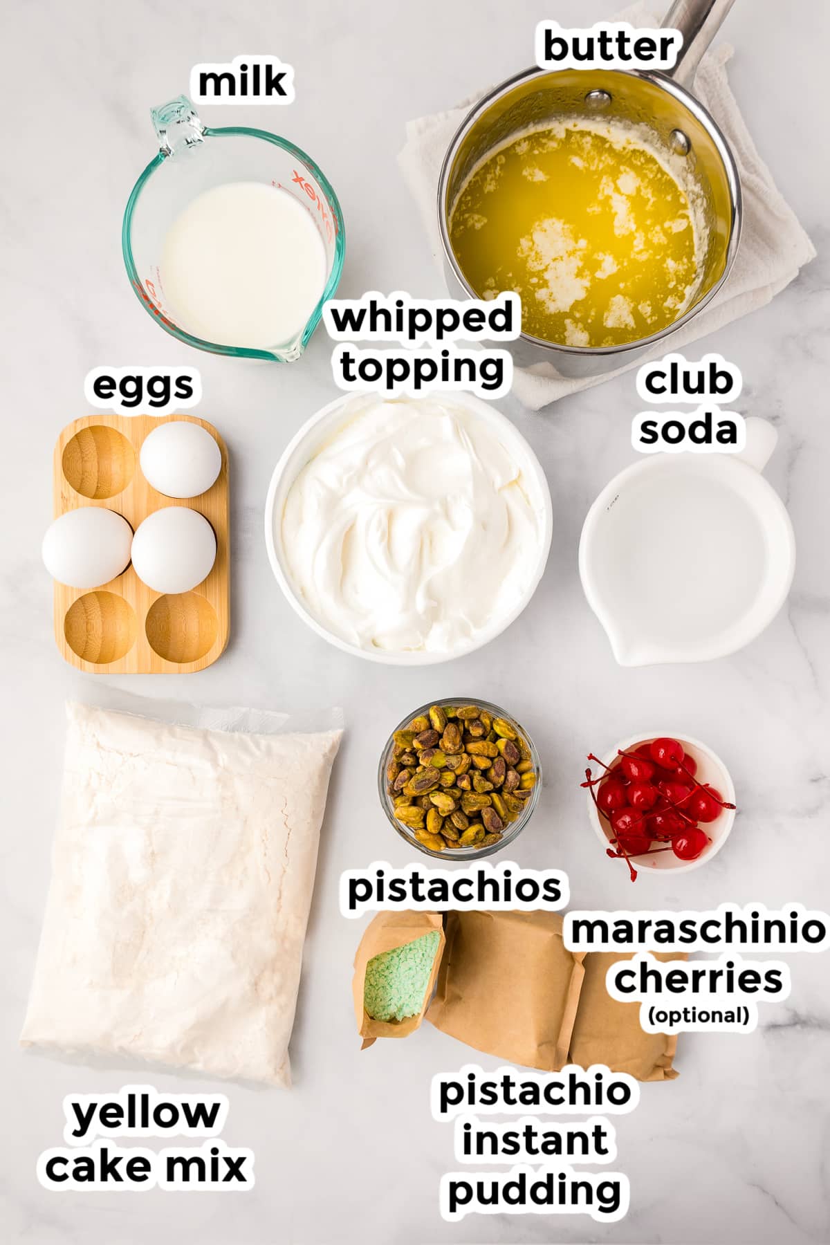 Ingredients for pistachio pudding cake in bowls on a counter from above with text labels.