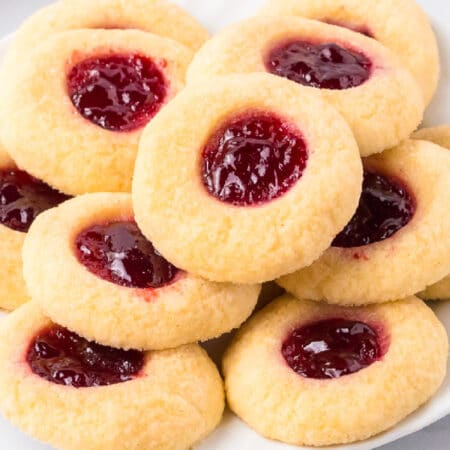 A wide view of a plate of raspberry thumbprint cookies.