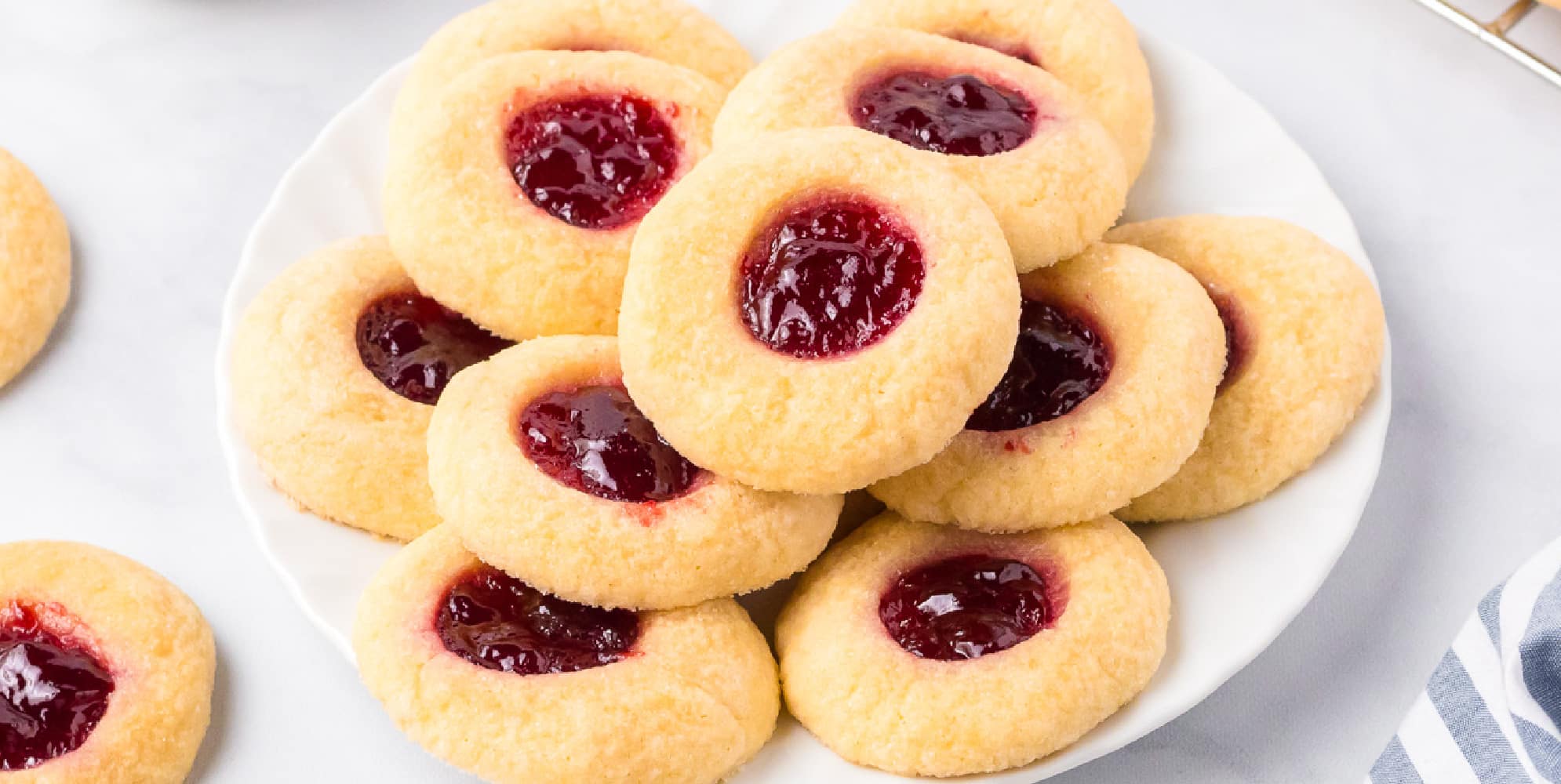 A wide view of a plate of raspberry thumbprint cookies.