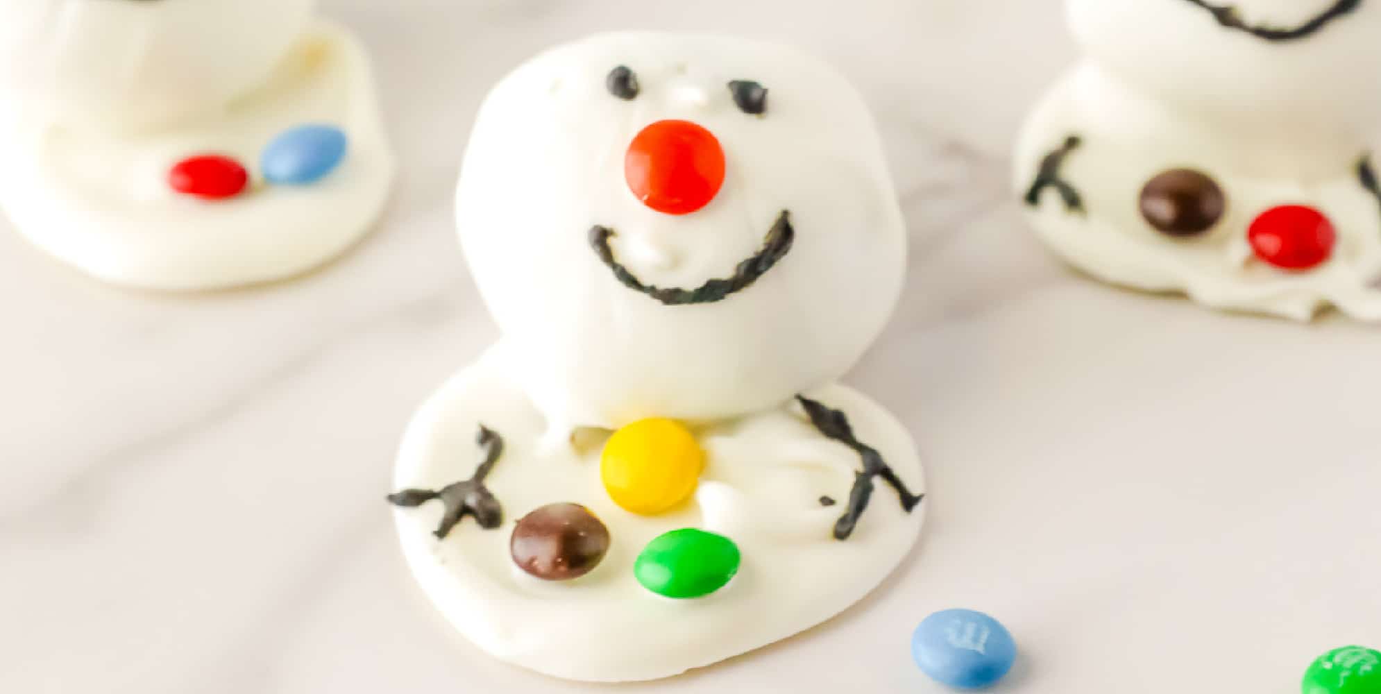 Wide view of a white chocolate oreo ball decorated like a melting snowman.