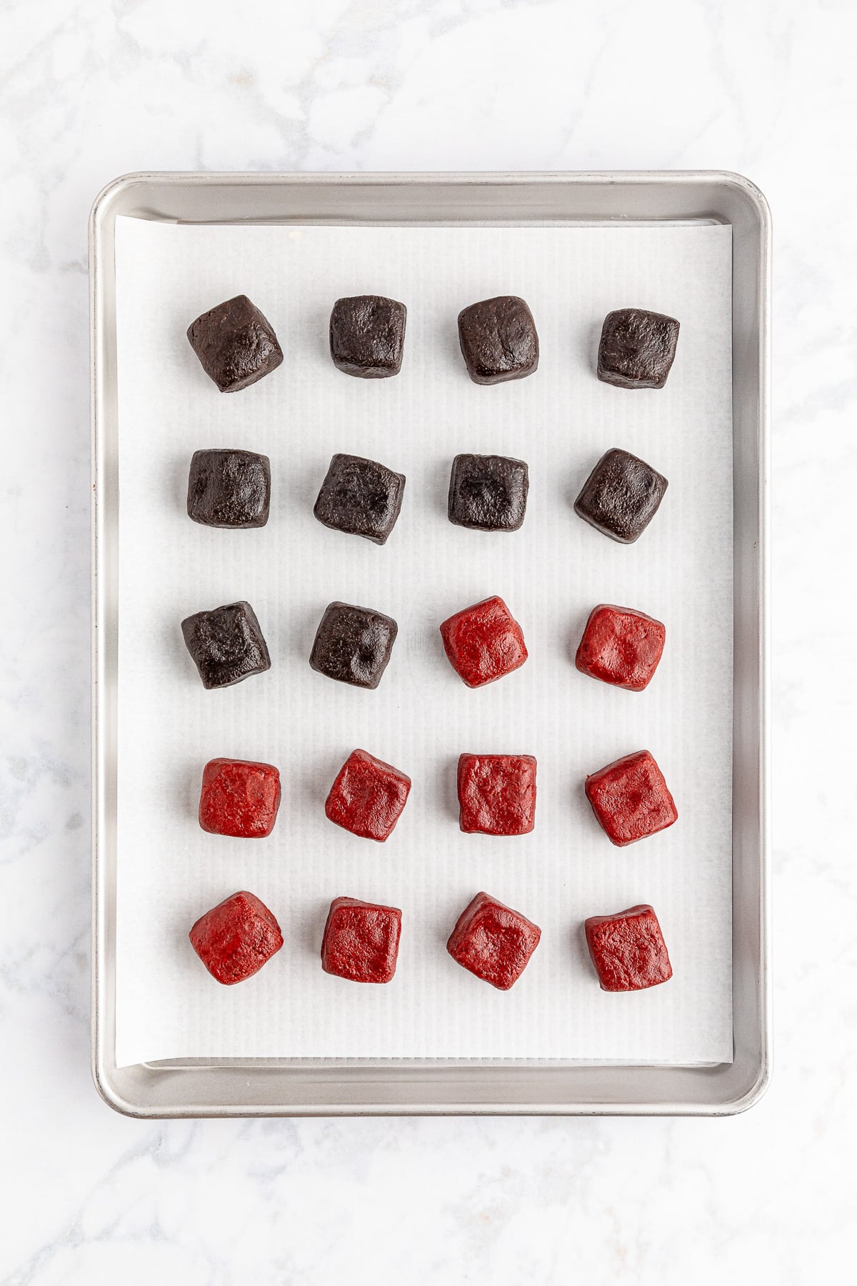 A baking sheet with square truffle dough portioned out and shaped into squares.