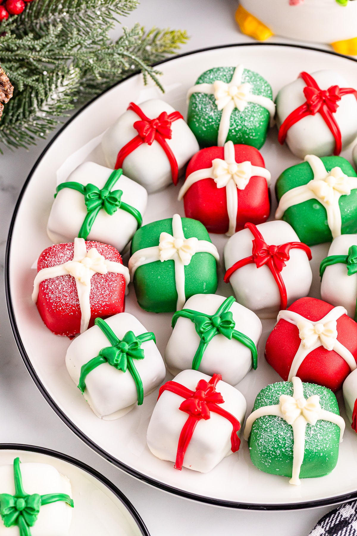 A plate of christmas present truffles with red, green and white bows.