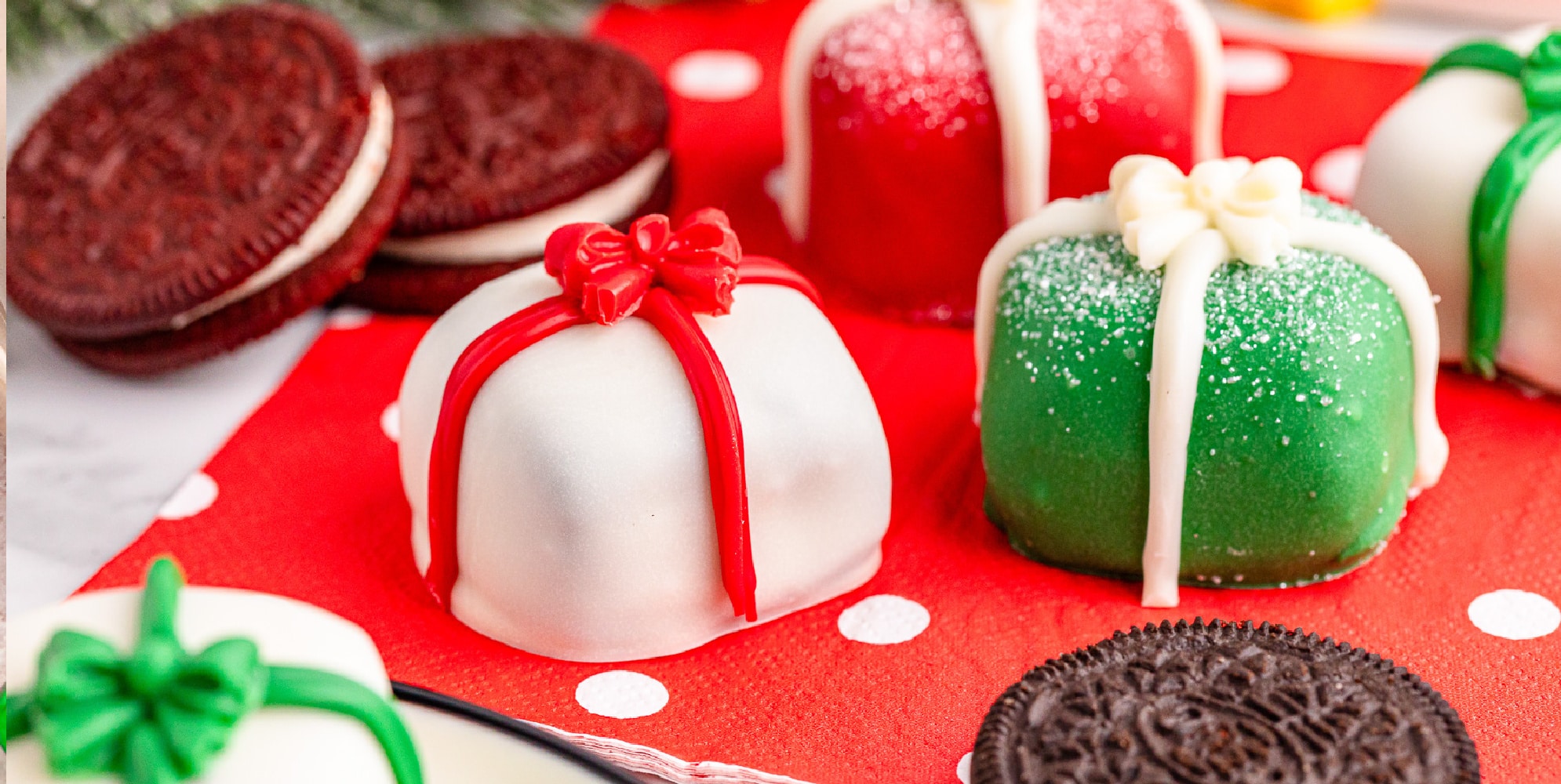 Christmas oreo truffles shaped like present on a napkin with red, green and white decorations.