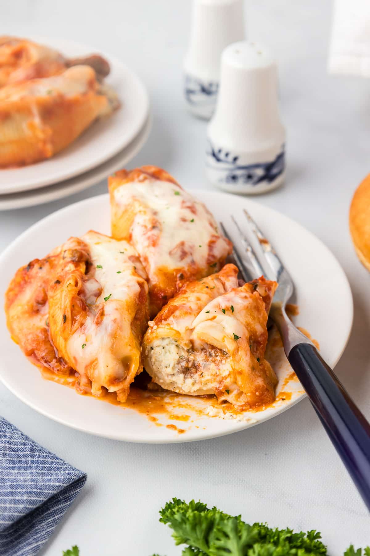 Chicken stuffed shells on a plate next to a fork.
