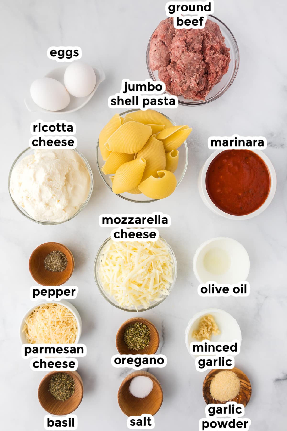 Ingredients for a stuffed shells with beef in bowls on a counter from overhead with text labels.