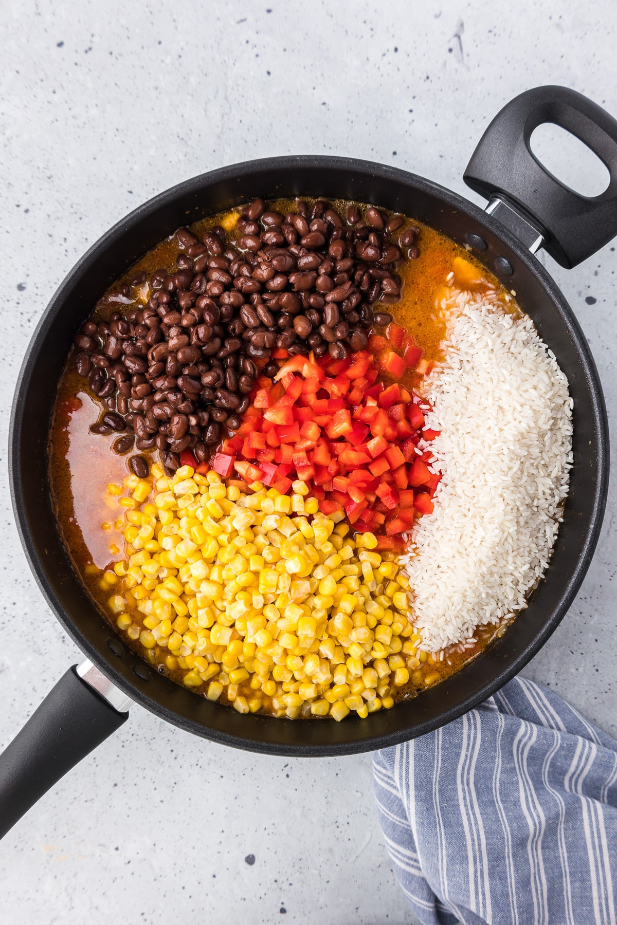 Mexican chicken and rice in a pan with black beans, diced red pepper, corn and rice in a tomato liquid.