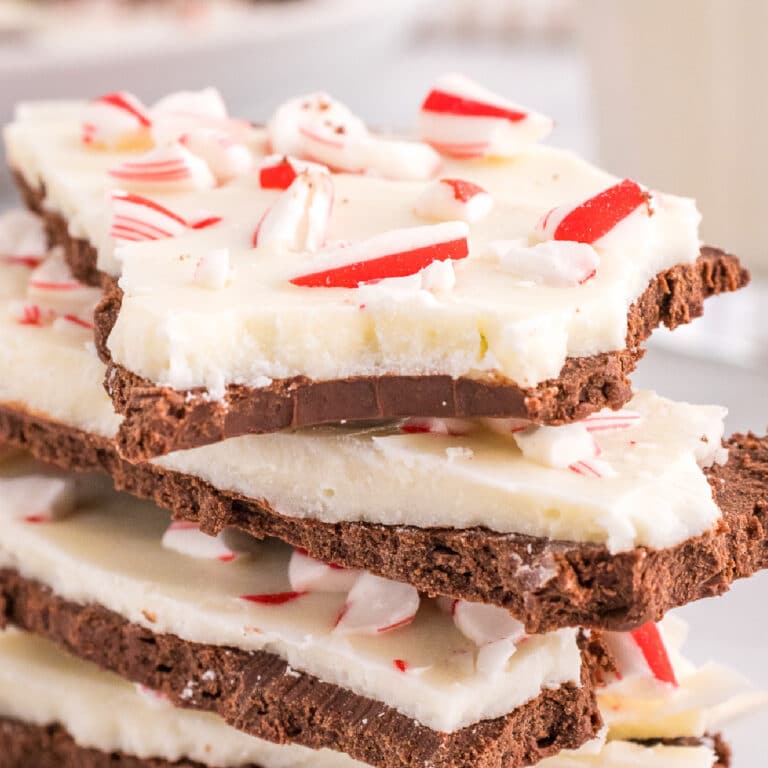 Peppermint bark stacked on top of each other close up with the top piece missing a bite.