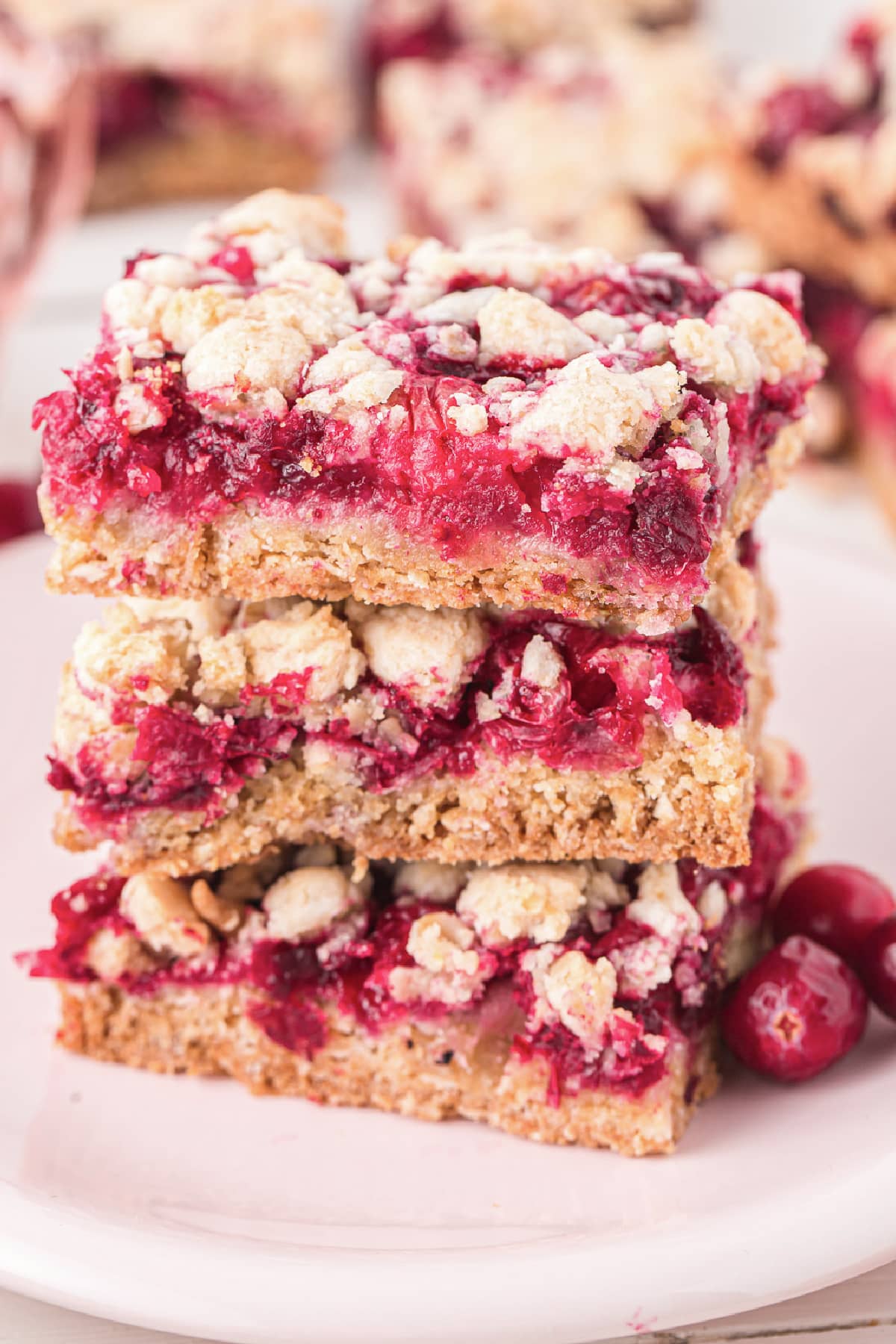 A stack of cranberry crumble bars on a plate.