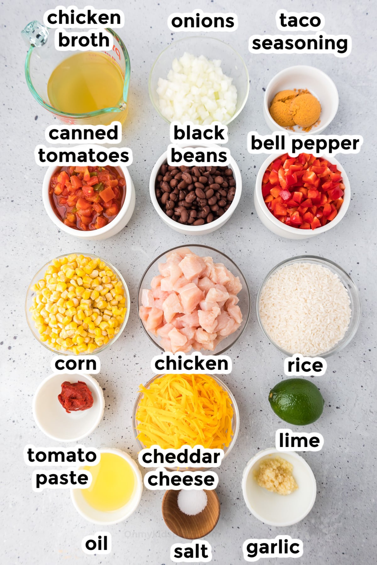 Ingredients for mexican chicken and rice in bowls on a counter from overhead with text labels.