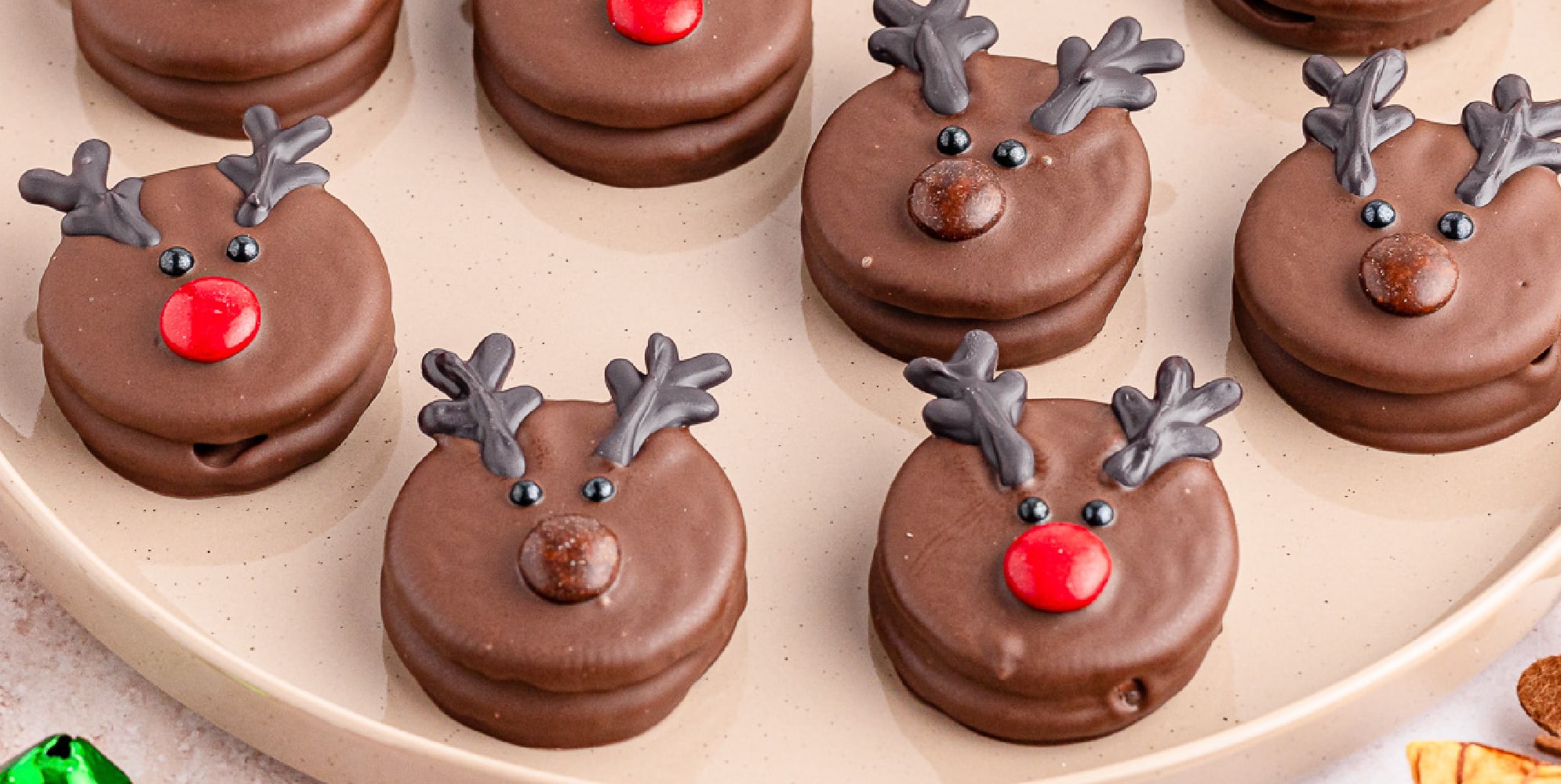 Chocolate dipped reindeer oreo cookies on a plate.