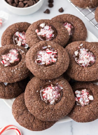 Chocolate peppermint cookies on a plate filled with a chocolate filling topped with crushed candy canes.