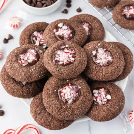Chocolate peppermint cookies on a plate filled with a chocolate filling topped with crushed candy canes.