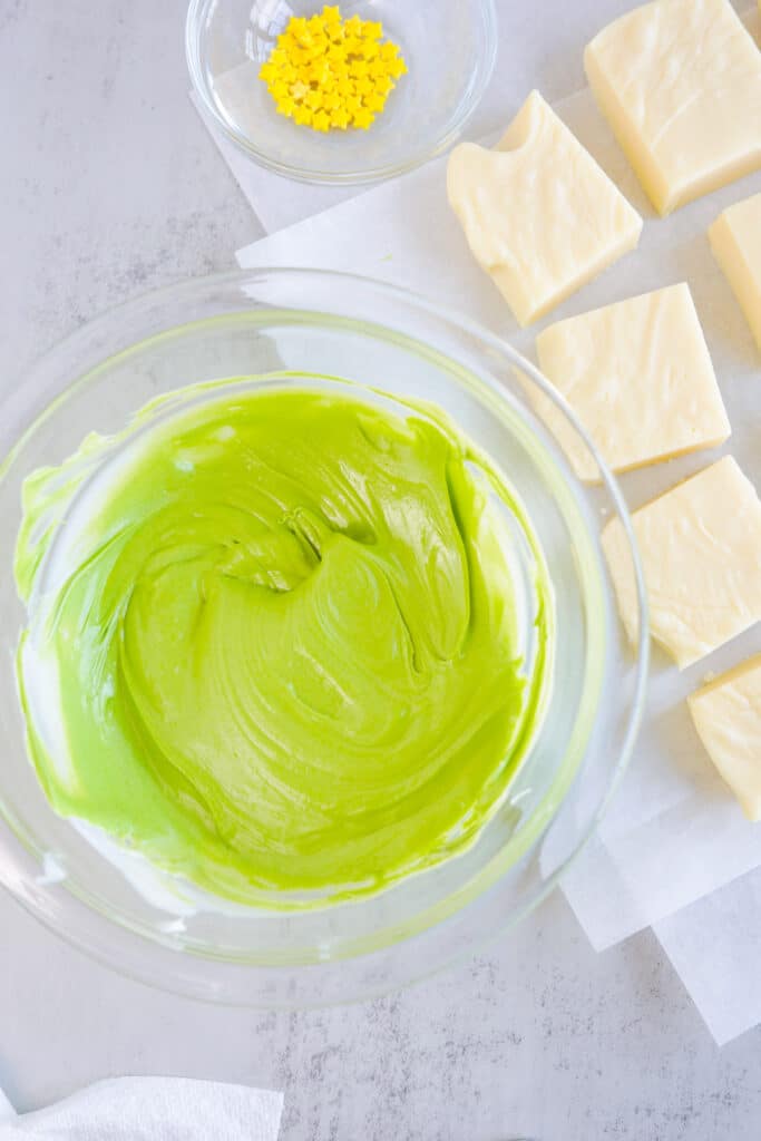 A bowl of green chocolate melted next to vanilla fudge.