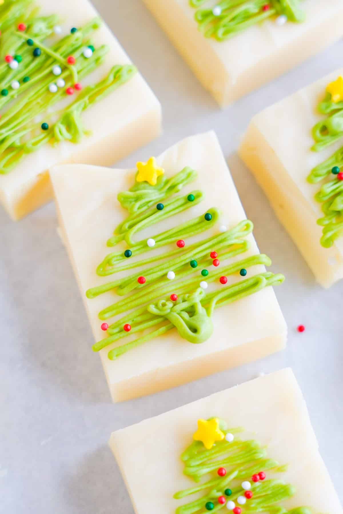 Holiday vanilla fudge decorated with green chocolate Christmas trees close up on parchment paper.
