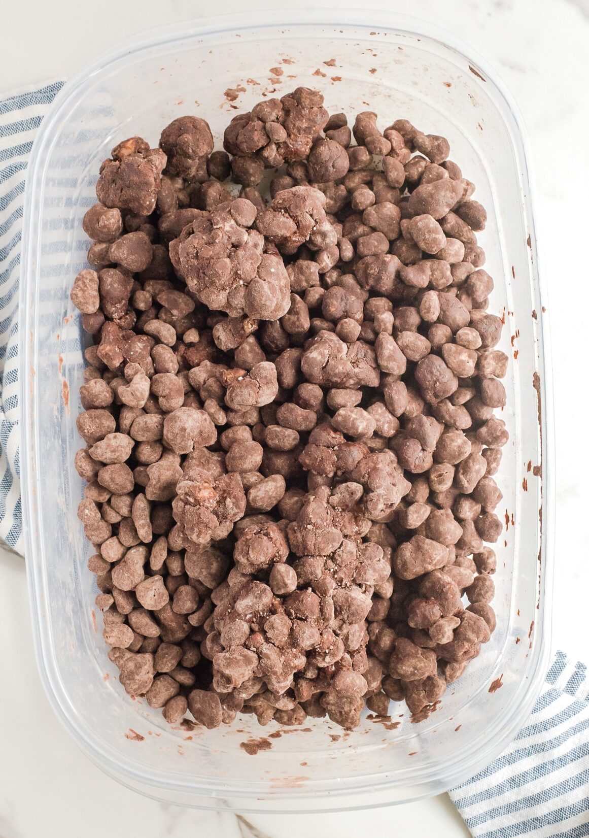 Chocolate reindeer poop snack mix in a large container coated in cocoa powder.
