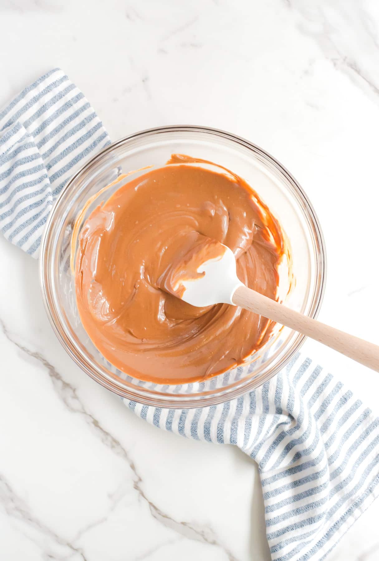 Chocolate and peanut butter melted in a bowl with a spatula stirring.