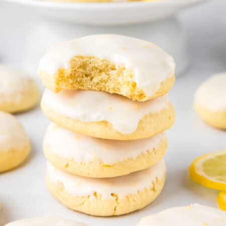 A side view of a stack of lemon cookies with a bite taken out of the top cookie.