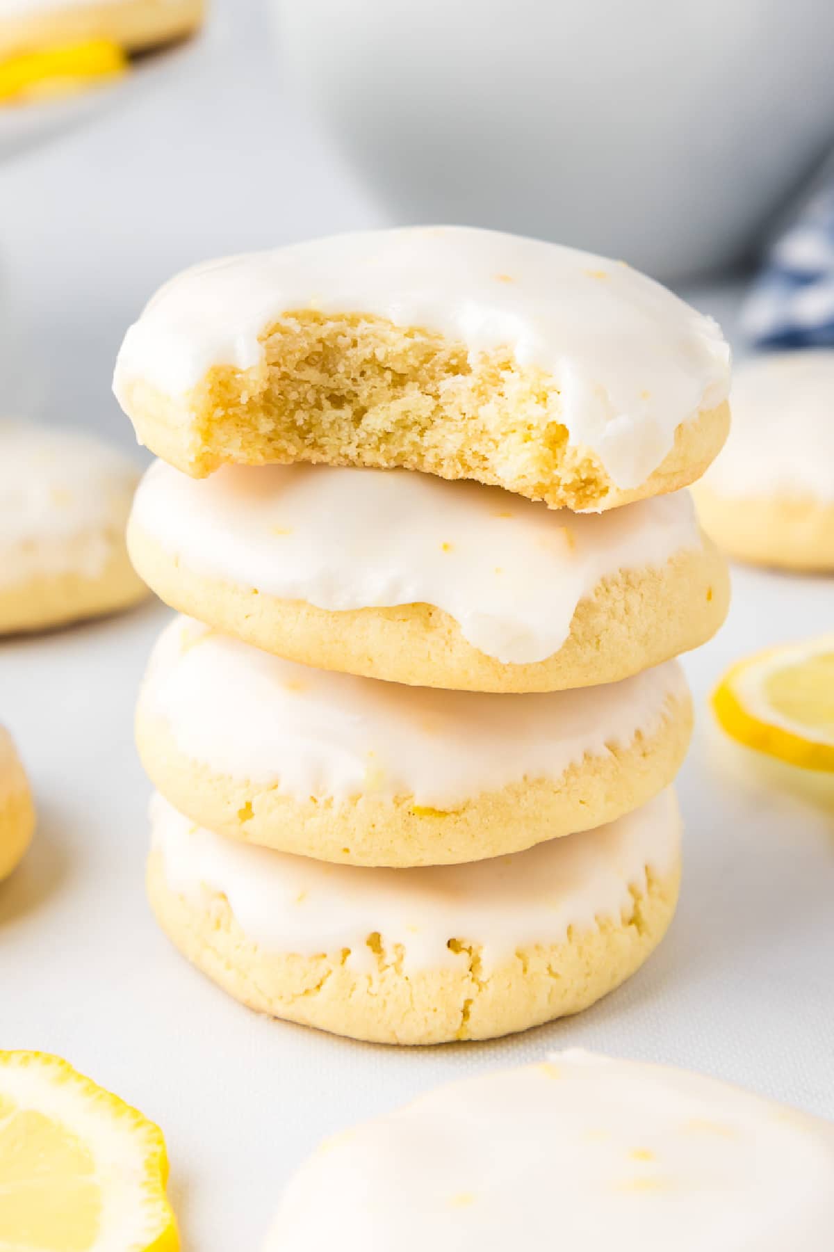 A stack of lemon cookies topped with glaze up close with a bite missing from one cookie..