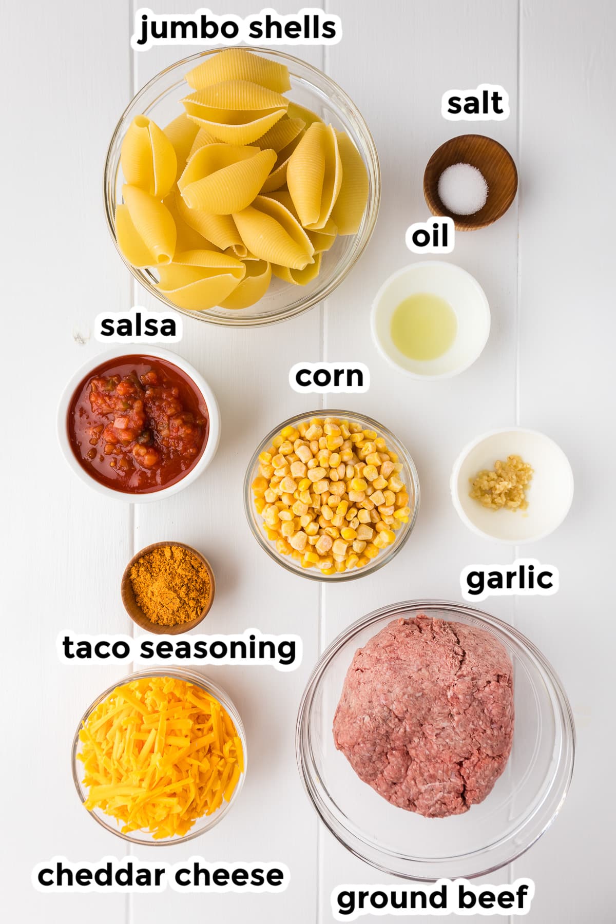 Ingredients for taco stuffed shells in bowls with text lables.