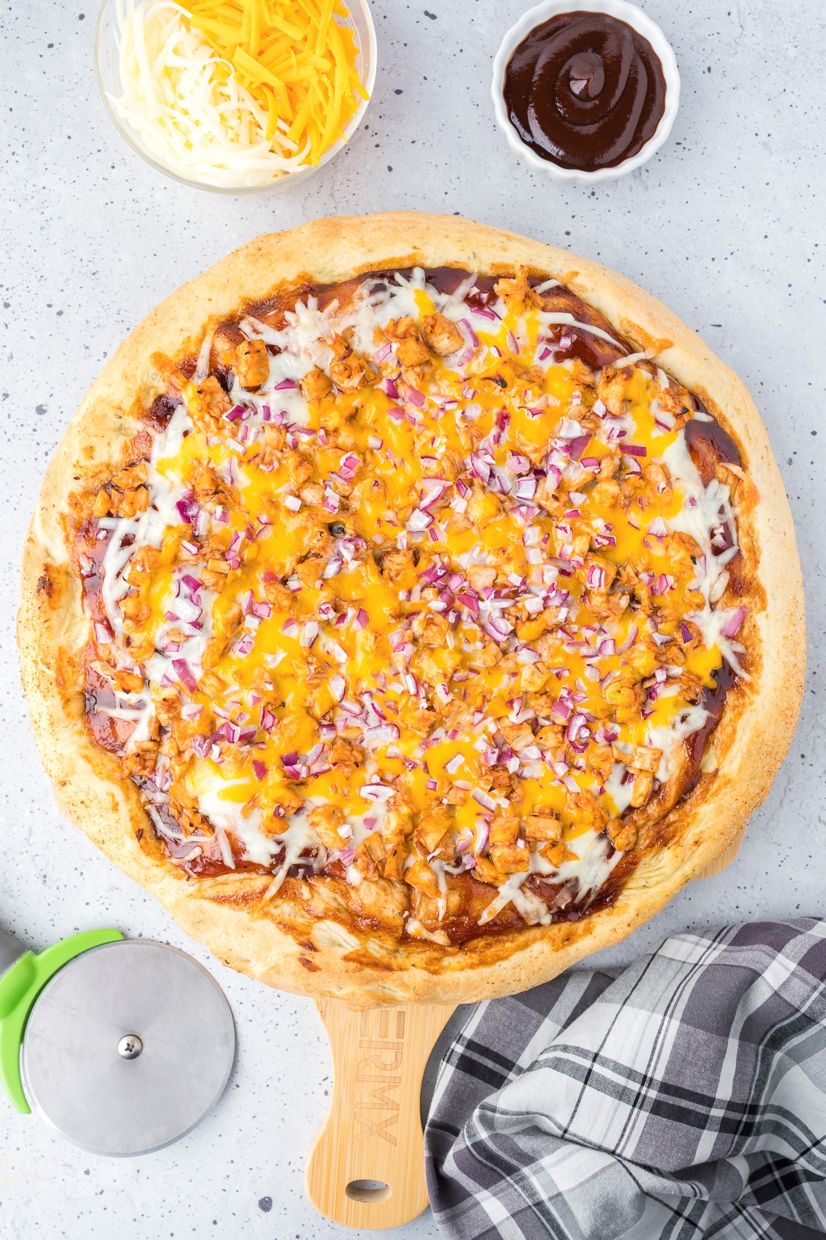 A bbq chicken pizza from above on a wooden cutting board after baking.