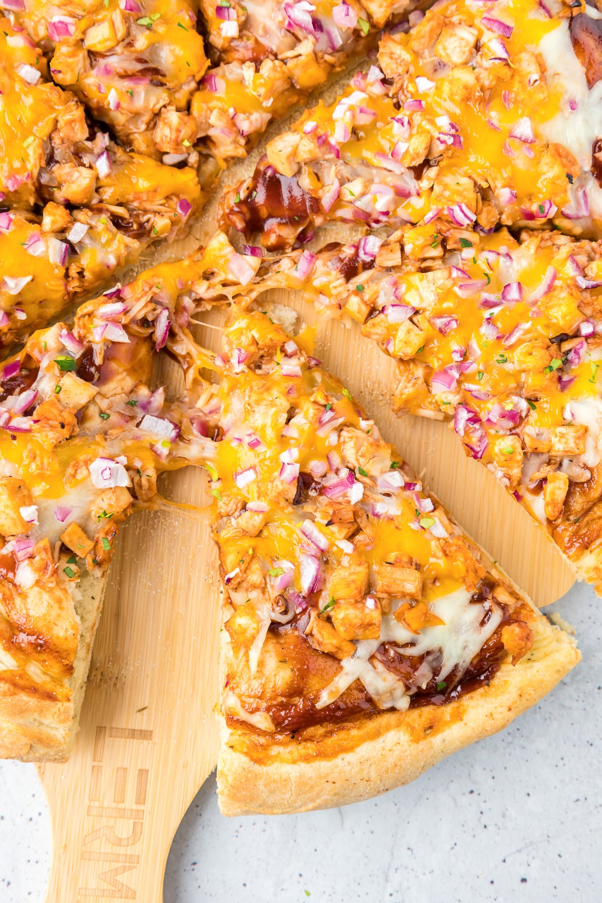 A bbq chicken pizza sliced on a cutting board.