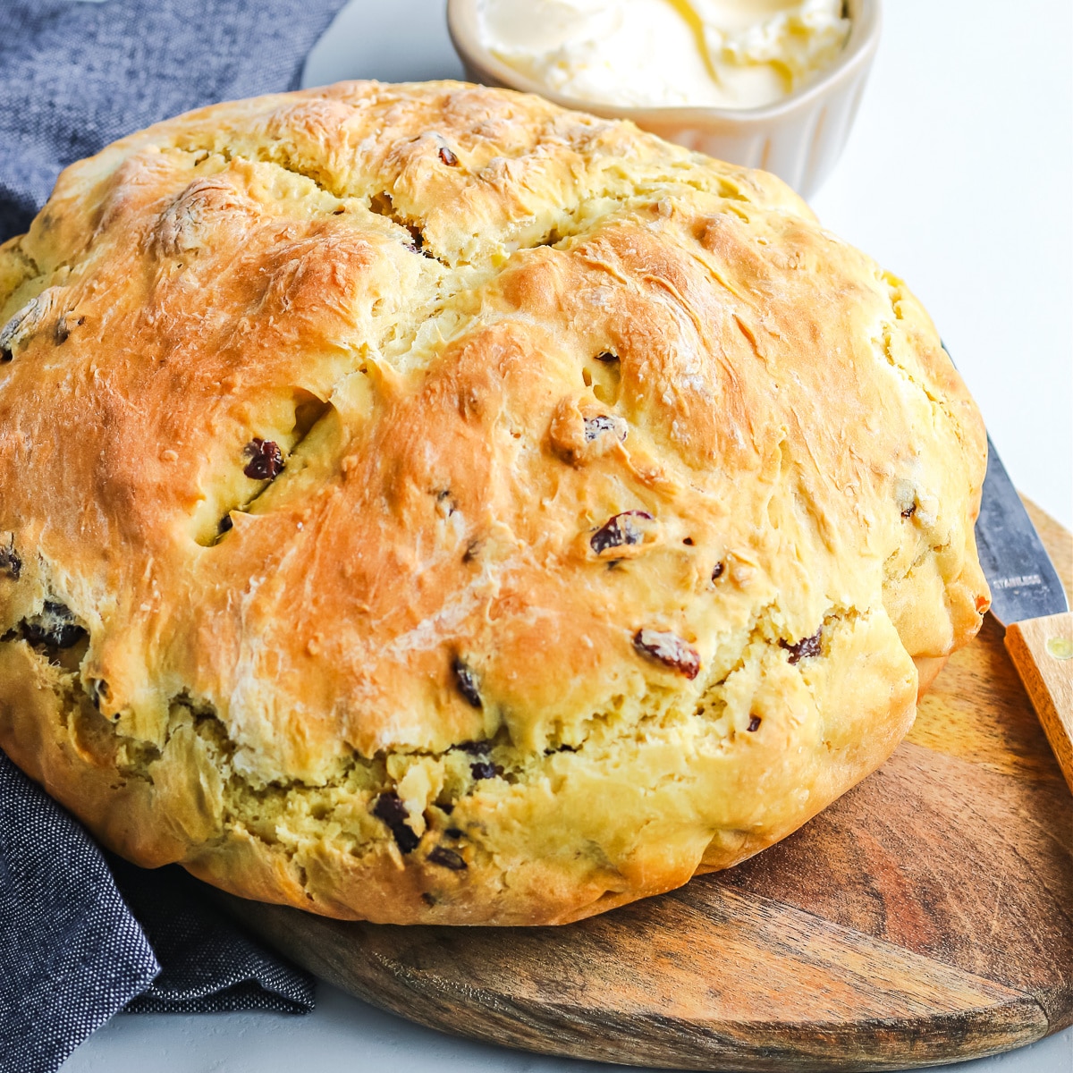 A loaf of Irish Soda bread sitting on a cutting board full of raisins before slicing.