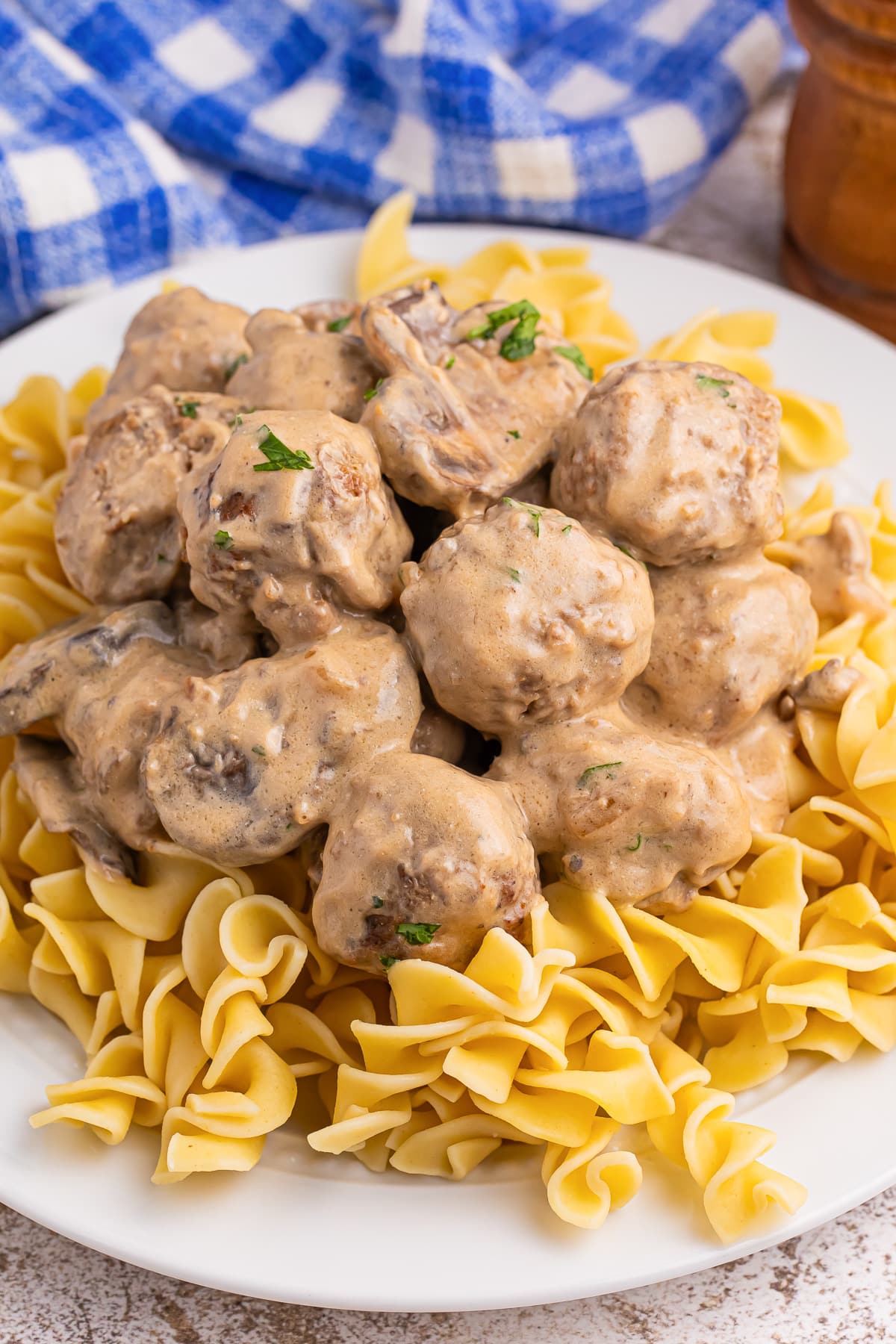 Meatball stroganoff on top of egg noodles on a plate.