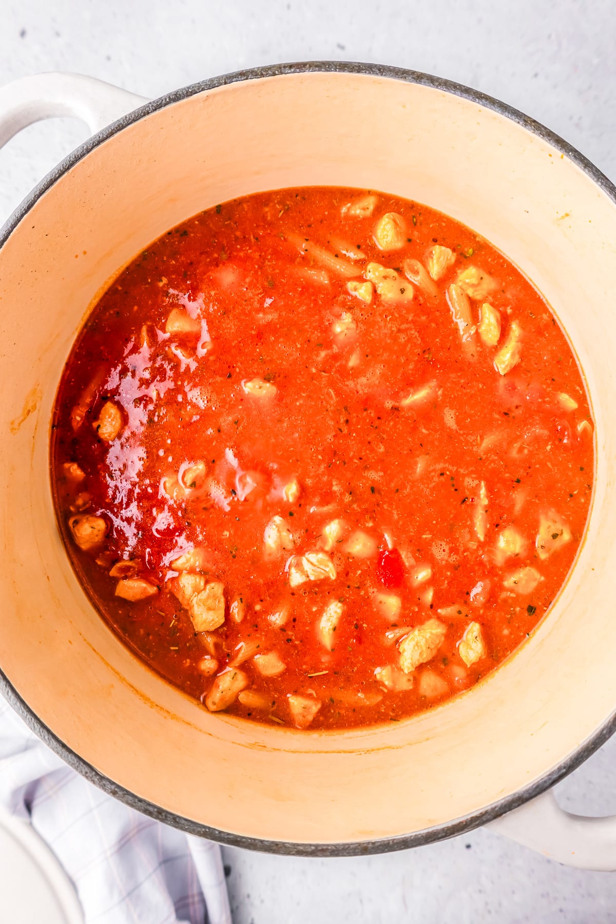A pot of tomato soup with chicken in it.