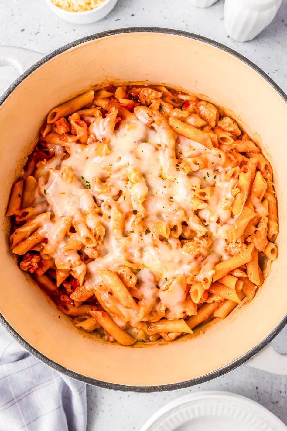One pot chicken parmesan pasta covered in parmesan and mozzarella cheese in a pot from above.