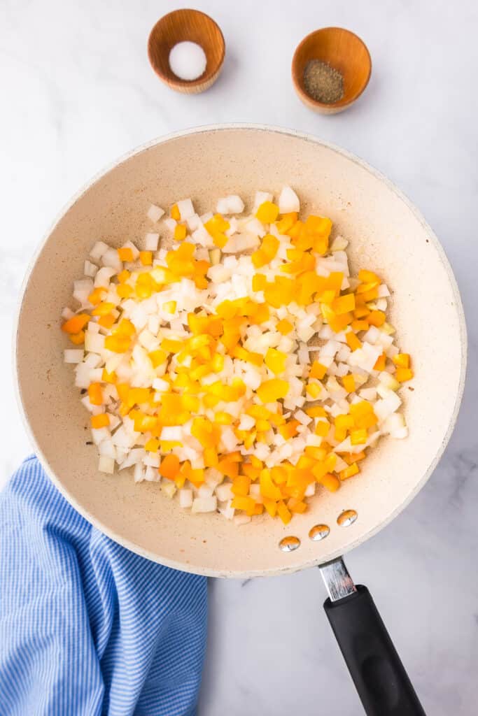 A skillet filled with chopped onions and bell pepper in a pan.