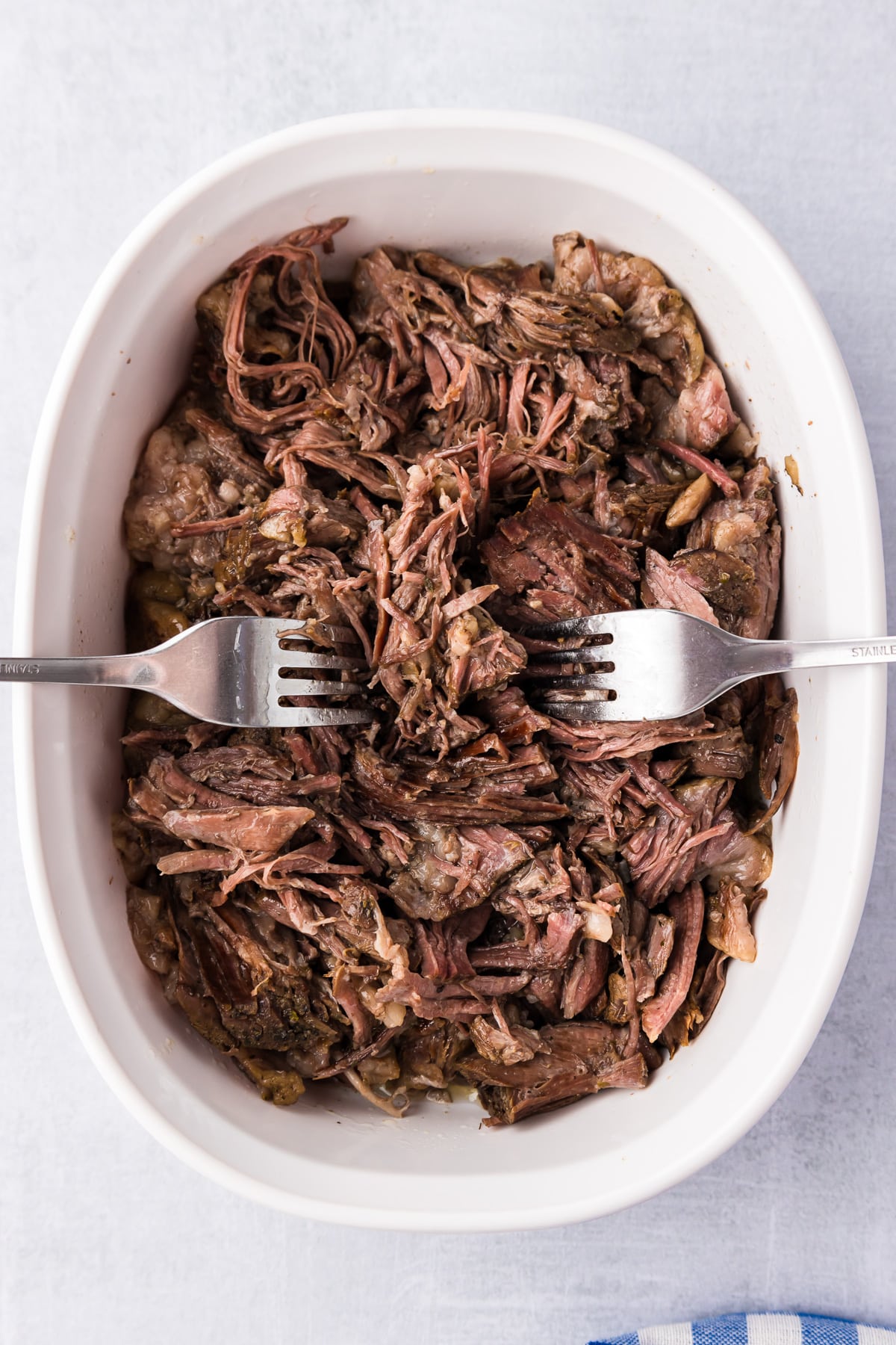 A bowl of shredded beef with two forks from above.