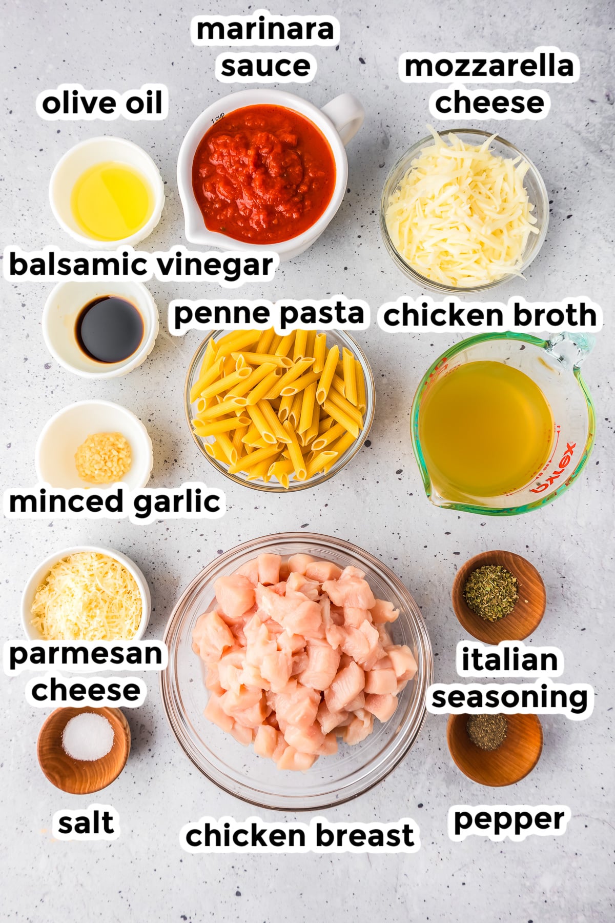Ingredients for one pot chicken parmesan pasta in bowls on a counter with text labels.