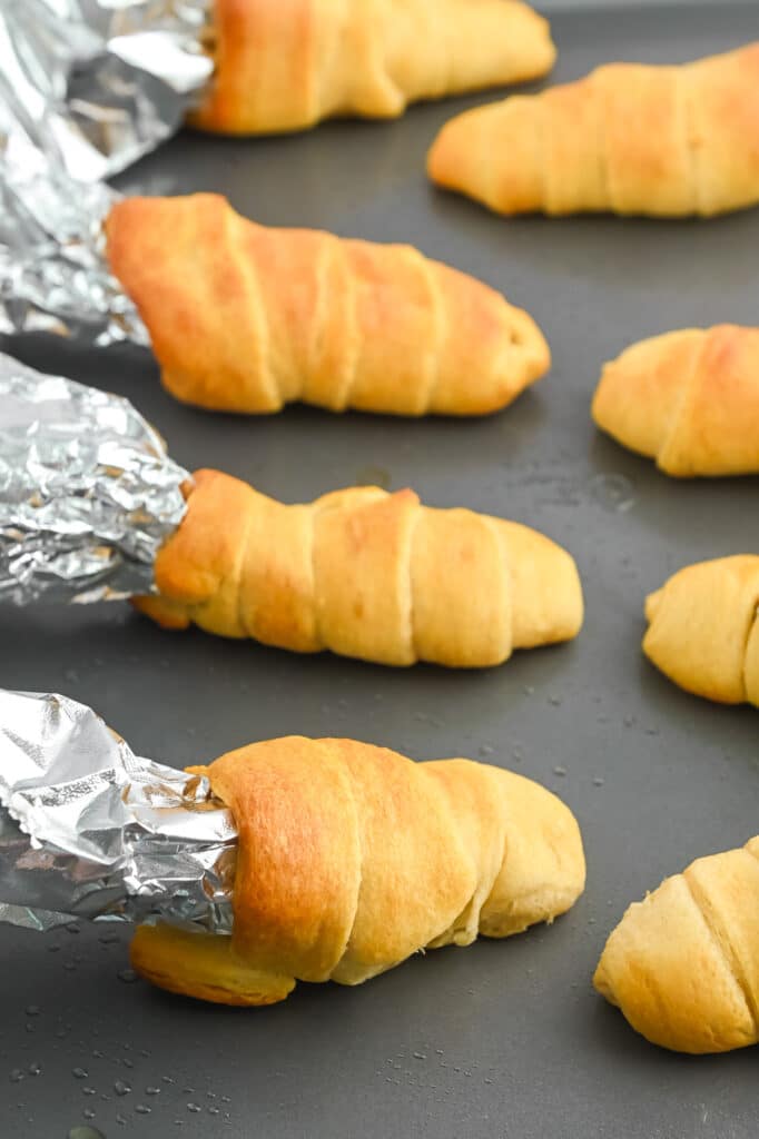 Tin foil inside coming out of baked crescent rolls on a baking sheet.