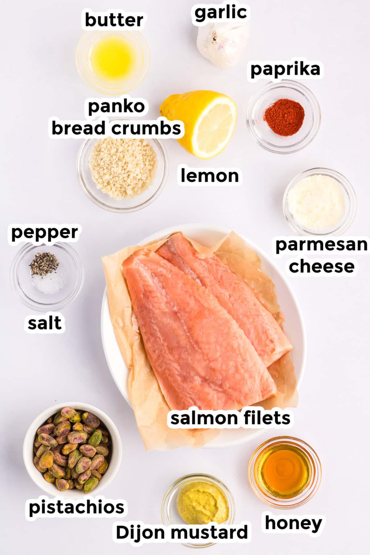 Ingredients for crusted pistachio salmon on the counter in bowls with text labels.
