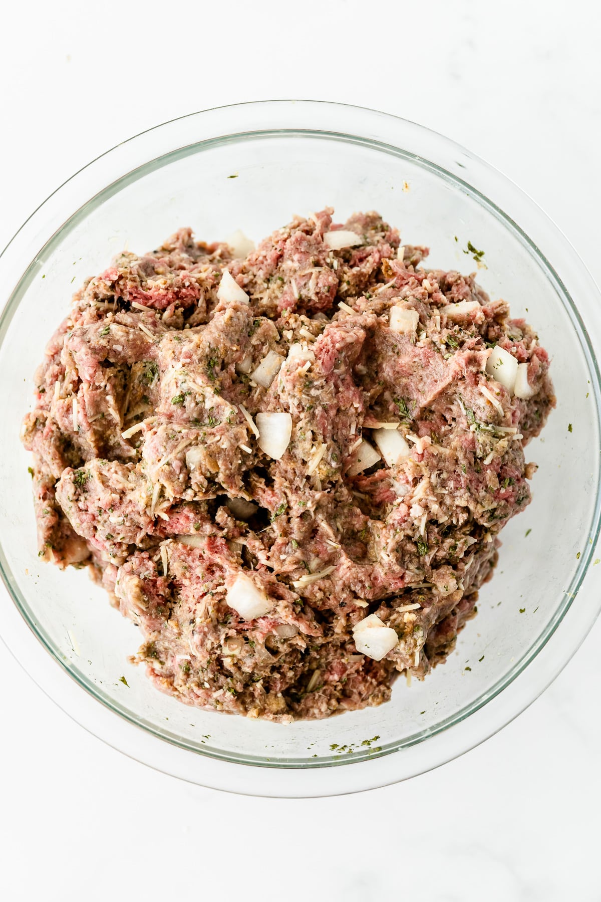 A bowl of raw ground beef meatloaf mixture in a large mixing bowl.