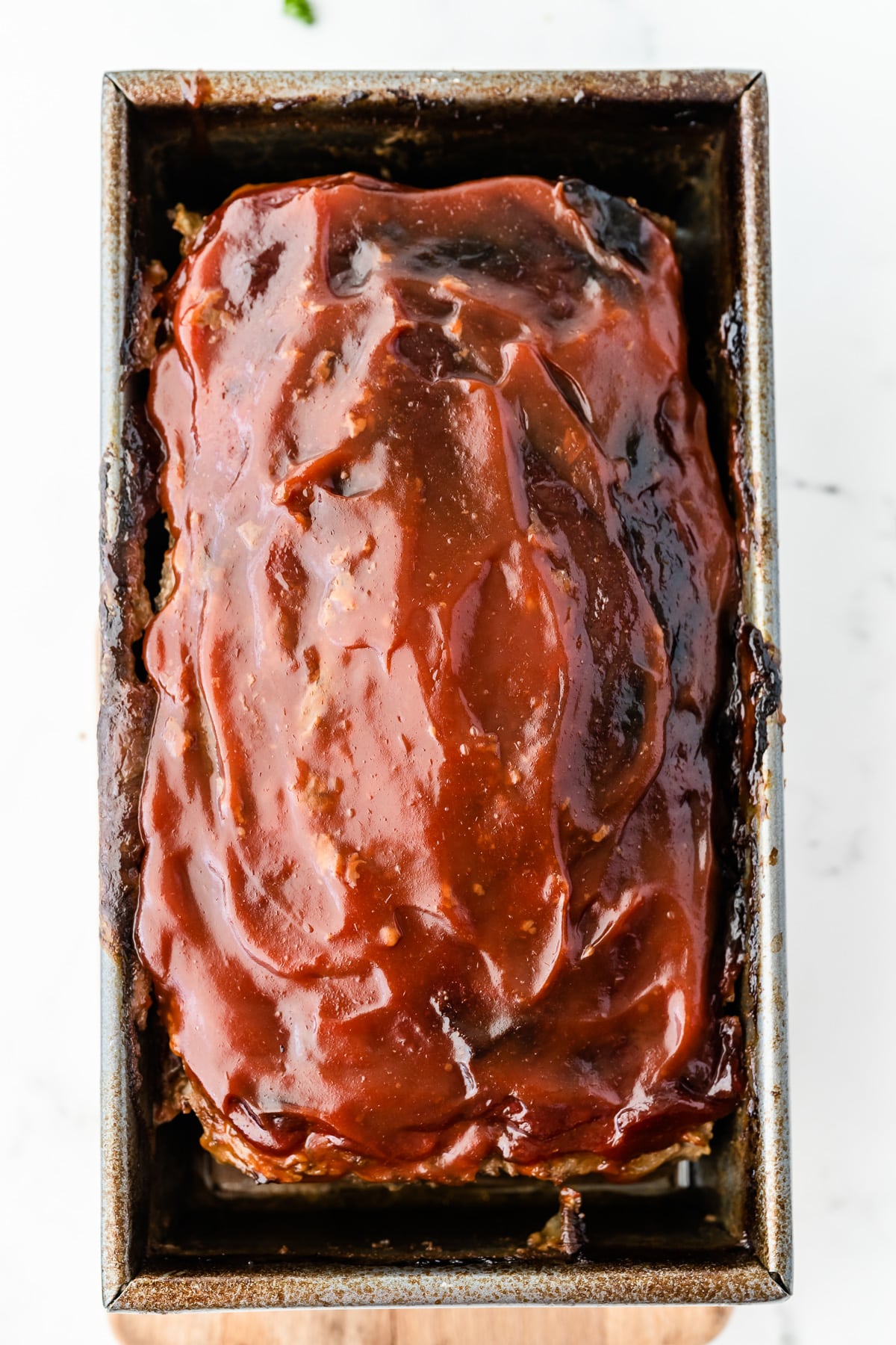 A meatloaf cooked in a pan with a sauce on top.