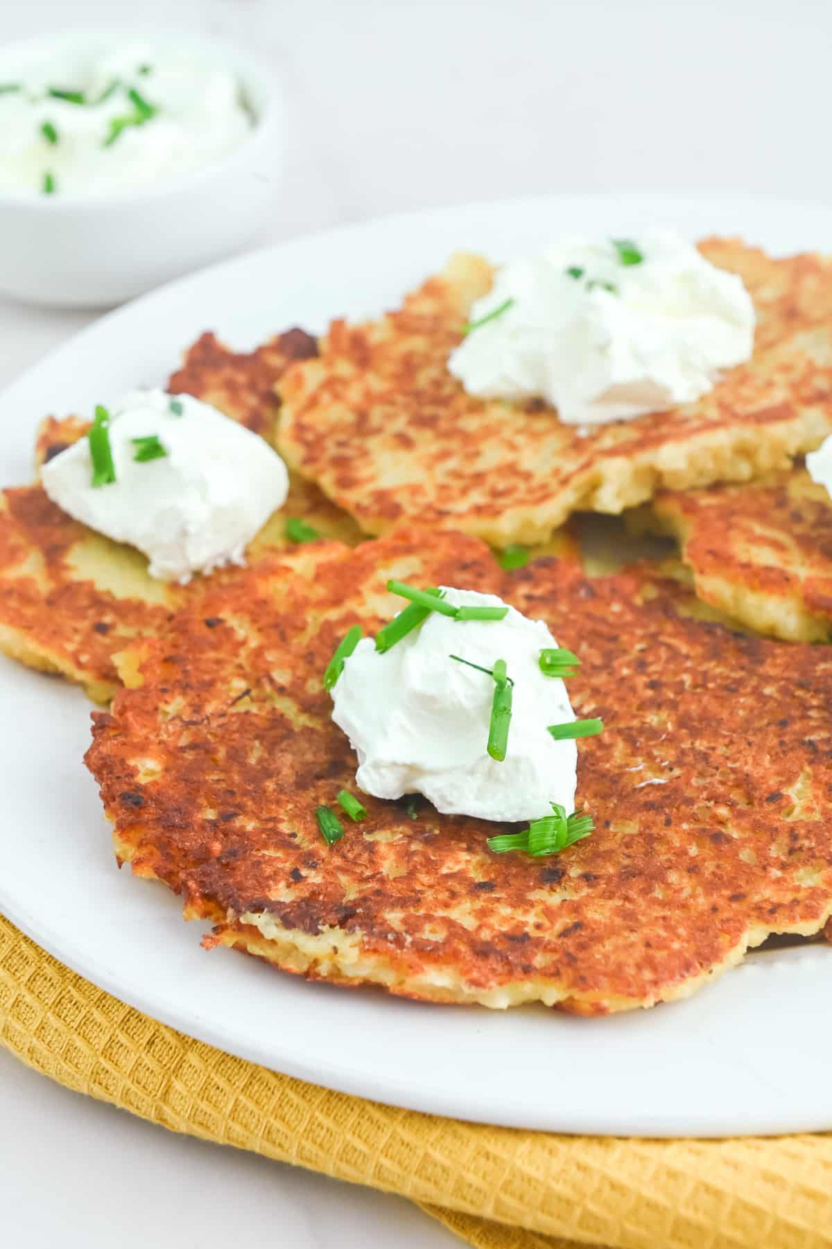 Potato pancakes with sour cream and chives on a plate.