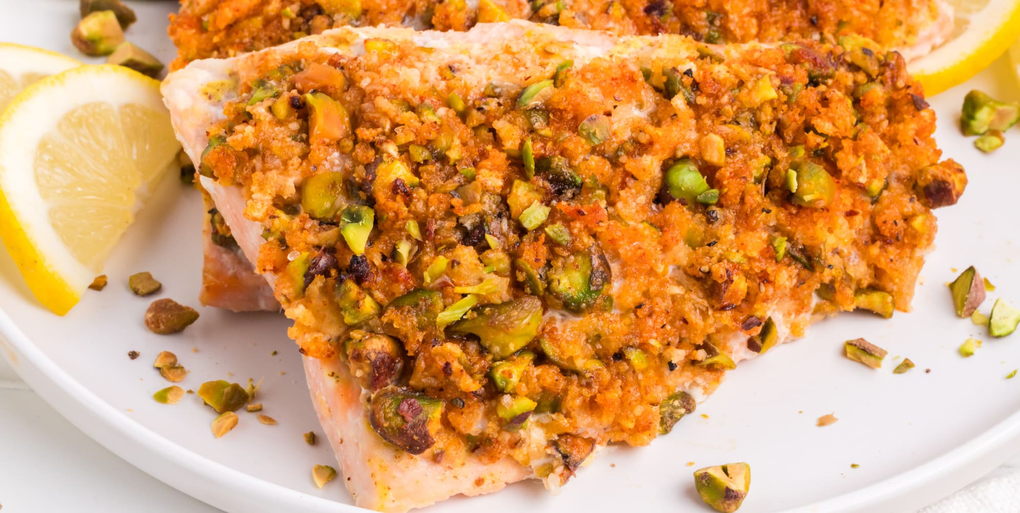 A wide view of a piece of pistachio crusted salmon on a plate.