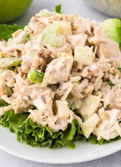 Apple walnut chicken salad piled high on a piece of lettuce on a plate.